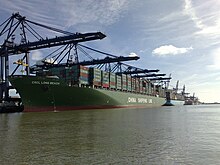 Green container ship moored alongside a dock