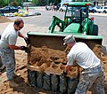 Filling multiple sandbags with a front-end loader.