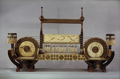 A seat by Carlo Bugatti of wood and parchment with inlays of hammered brass, painted decor and fringe (c. 1900)