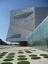 Modern building in bright sunlight with circles of grass in foreground