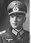 A man wearing a peaked cap and military uniform with an Iron Cross displayed at the front of his uniform collar.