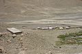 A view of Everest North Base Camp looking west, August 3, 2002. The permanent structure at left is for mountain climbers, central-left structure is for pit toilets, while the temporary wood-frame, plastic tarpaulin-covered structures below and right are for other visitors and support people