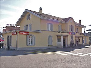 Two-story station building with yellow walls and gabled roof