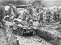 Men carrying mortar bombs by their attached carrying straps