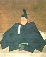 Portrait in three-quarter view of a person seated on the floor in courtly attire carrying a stick like object.