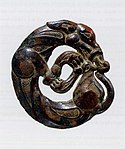 狼纹青铜车马饰，为宁夏南部及甘肃东南的游牧文物中所特有。公元前5~4世纪（战国中晚期）。[26][24]