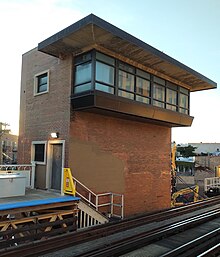 A 3/4 view of a brick tower with cantilevered windows.