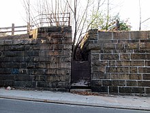 A stone embankment with a boarded-up staircase in the middle
