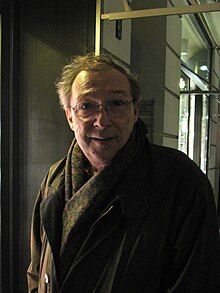 middle-aged white male wearing coat, scarf, and glasses, looking at camera