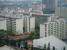 Several apartment blocks behind a building and a tennis court