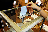 A voter putting her envelope into a clear ballot box during the 2007 French presidential election