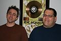 Jason Livermore and Bill Stevenson standing in front of the gold record for The Suffer & the Witness.