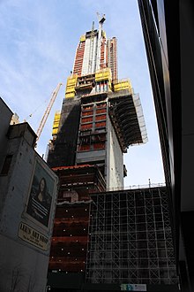 A cantilevered platform extends from the right side of the building under construction