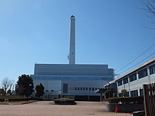 The outside of a large building with a large chimney protruding.