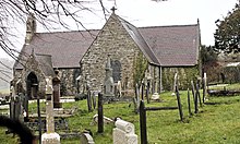 A stone single-story church in a graveyard.