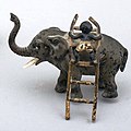 A black boy climbing up an elephant with a ladder. This one is identical to the lost figurine (NF.1914-0491).