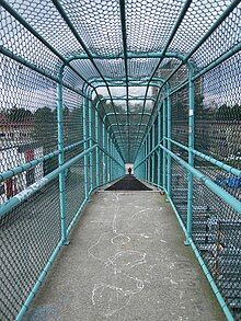 walking inside a wire mesh pedestrian bridge