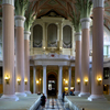 interior of the church, view to the organ, light pink columns, grey benches, dark green ornaments on the floor, organ case white and gold