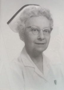 Image of a middle-aged woman wearing spectacles, a white nurse's cap, and a white coat