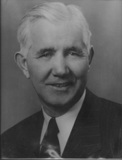 Portrait of a smiling McMillin in a suit