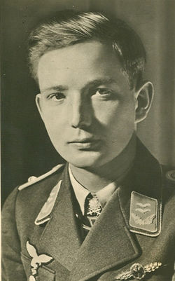 The head and shoulders of a young man, shown in semi-profile. He wears a military uniform with an Iron Cross displayed at the front of his shirt collar.