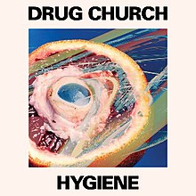 A beige square with a picture of an orange cut in half with a mitochondria model within the orange. Above the image reads "DRUG CHURCH" in black, all capital letters. Beneath the image reads "HYGIENE" in black, all capital letters.