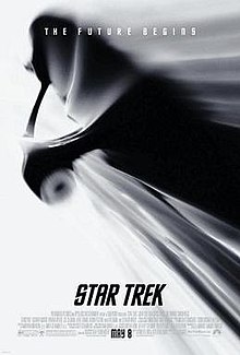 A Monochrome image of the USS Enterprise, a starship, traversing through space, through a white background. The tagline on top reads "The Future Begins".