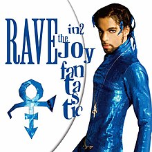 Prince wearing a blue, skin-tight outfit stands in front of a white background, staring into the camera.