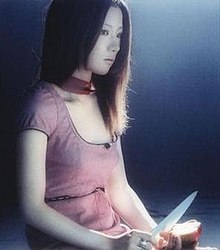 A woman stares off to her left, while cutting an apple in her hands.