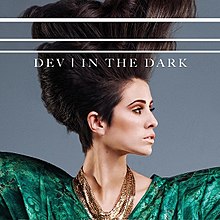 The cover art depicts a closeup of Dev with her hair raised up and looking to the side. At the top of the image, the words "Dev - In The Dark" are written in all caps.