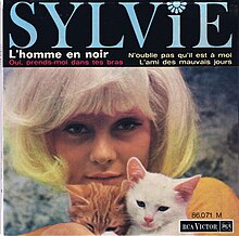 A photograph of French pop singer Sylvie Vartan holding two cats