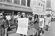 Women holding signs reading "Let's judge ourselves as people" and "Can make-up cover the wounds of our oppression?"