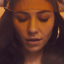 A color photograph of Marina Diamandis wearing a translucent orange visor.