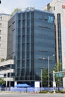 An image of a building with the text "JYP" on the upper side.