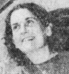 A young white woman with dark curly hair, smiling from an ambulance window