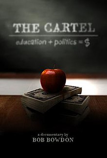 Red apple on top of stack of money on desk in front of a classroom blackboard. Blackboard reads "education + politics = $"