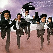 A line of five men in suits, running in the desert.