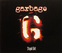 A stylized "G" resembling a branding iron. Above is "Garbage" in neon-like letters, and below "Stupid Girl".
