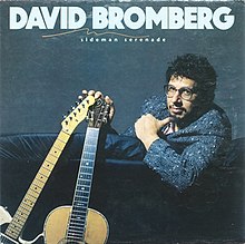 David Bromberg sitting on a couch, with an electric guitar and an acoustic guitar