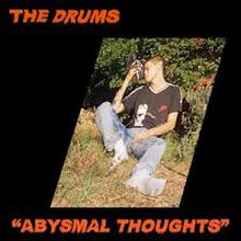 A photo of a man leaning against a bush and holding a shoe to his head. There is a black border with the orange text "The Drums" in the top-left and ""Abysmal Thoughts"" in the bottom-right.