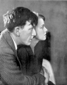 Young white man and woman in right profile, he embracing her, their hands clasped together