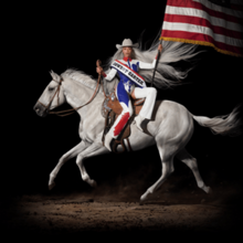 Beyoncé with long white hair sits reverse side-saddle atop a white horse. Her cowboy outfit is in the colors of the American flag, which she holds, only the red and white stripes visible.