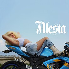 Stan laying over a motorcycle, sporting a wig and white underwear, barely covered by a pair of distorted jeans.