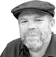 Portrait photograph of Rafael Corrales wearing a flat cap and black shirt