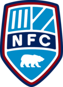 A shield with the letters "NFC" in the middle and the remainder divided into three sections, the top left corner containing three white stripes and the top right two white stripes. In the bottom section is a polar bear rearing on all fours. All on a blue background