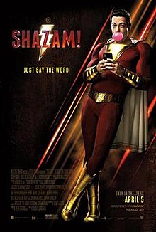 Shazam, a hero in a red costume with a gold cape, uses his phone while blowing bubblegum. To his left, the words "Shazam!" and "Just Say The Word" can be seen.