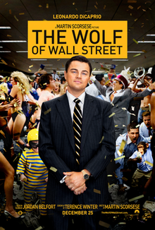 Leonardo DiCaprio in a tuxedo stands smiling, holding his hands together while it appears his office is either celebrating, going wild, or both. "The Wolf of Wall Street" (no quotes) is shown with black text on a yellow card above DiCaprio.