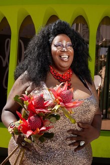 Lady Red Couture smiling and holding flowers