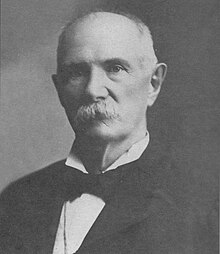 Black and white profile photo of Quintus Quincy Quigley with a large mustache, dressed in a suit