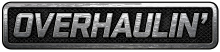 A simple logo spelling the word "Overhaulin' " in block capital letters in silver over what appears to be a car grill or interlaced gray mesh
